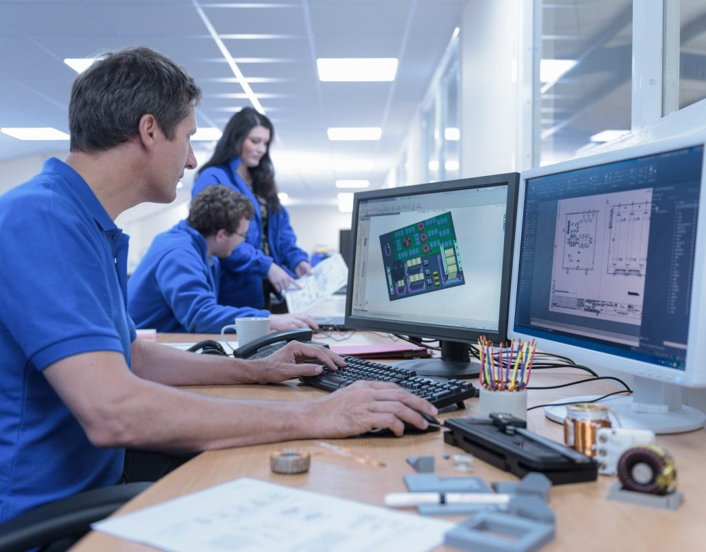 Electronics designers with CAD imagery in electronics factory